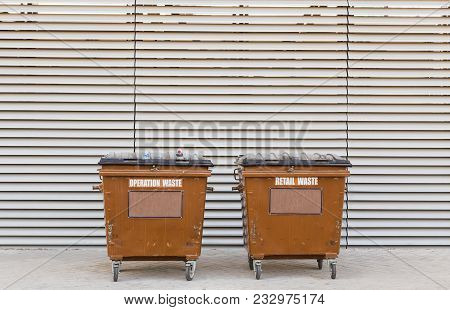 Two Brown Garbage Containers On A Monophonic Light Wall Background