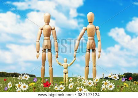 A Family Of Wooden Mannequins On A Lawn Surrounded By Flowers