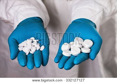 Various Pills In The Hands Of A Doctor Close-up. The Concept On The Production Of Medicines