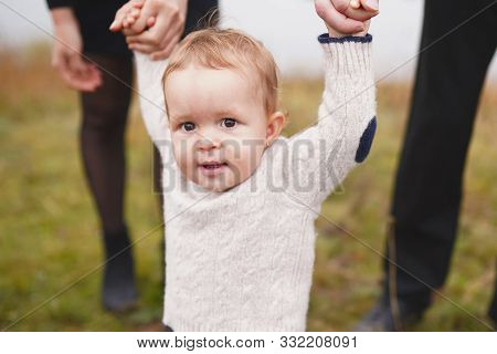 Parents Holds The Hand Of A Small Child Outdoors