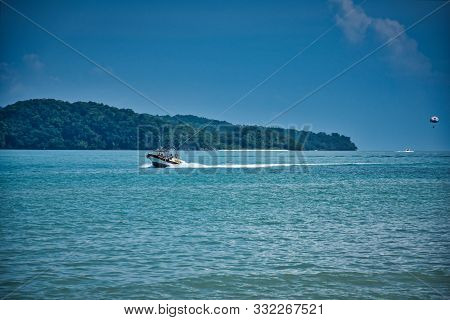 Parasailing On The Waves Of The Azure Andaman Sea Under The Blue Sky Near The Shores Of The Sandy Be
