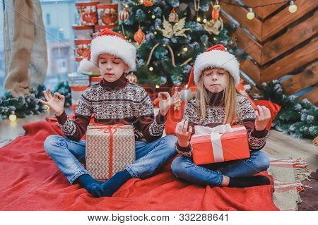 Interesting Photo Of Little Siblings Practicing Yoga On Red Carpet Home In Christmas Time.