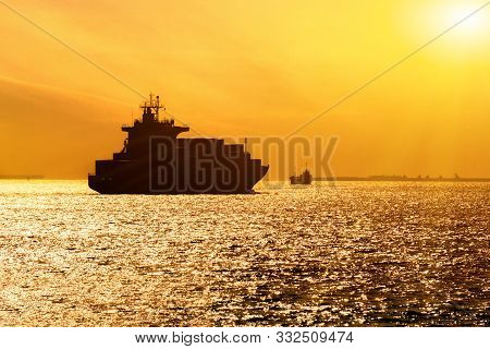 Silhouette Of Cargo Ship With Full Shipload Cargo Containers Are Sailing In The Osaka Bay Evening Wi