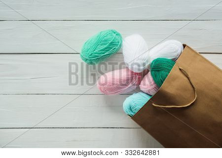 Scatter Oval Acrylic Colorful Wool Yarn Thread Skeins Lying With Kraft Paper Brown Package On White 