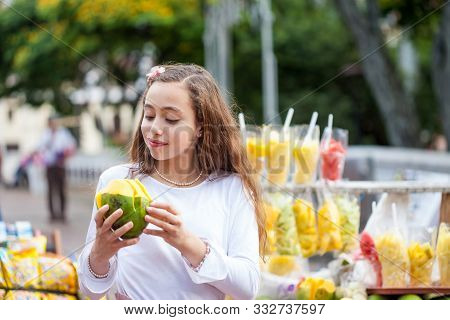 Beautiful Young Girl At Paseo Bolivar Square In The City Of Cali Eating Tropical Fruits In Colombia