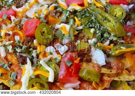 Close Up Of Take Out Box With Nachos Topped With Beef, Jalapenos,tomatoes, Onions And Cheese,