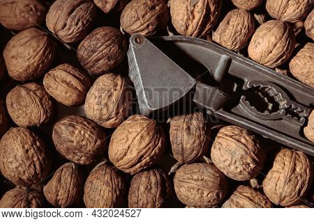 Walnut In A Nutcracker Close-up. Dark Background. Beautiful Background With Food. Healthy Ingredient