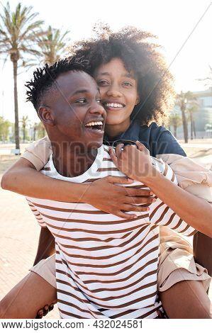 Vertical Portrait Of A Young African-american Couple In Love. The Girlfriend Piggybacking The Boyfri