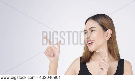 Young Smiling Woman Holding Invisalign Braces In Studio, Dental Healthcare And Orthodontic Concept
