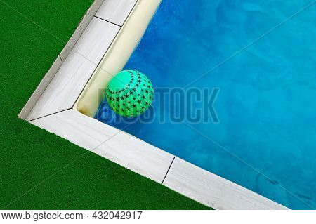 A Green Asterisk Ball Floats On The Surface Of The Water In The Pool