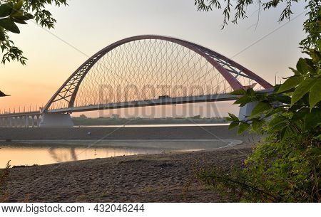 Bugrinskij Bridge Across The Ob River At Dawn. High Arched Cable Car Bridge Over A Wide River, Pink 