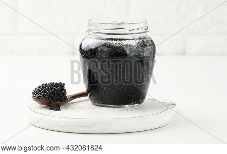 Fresh Black Paddlefish Caviar In A Wooden Brown Spoon And A Full Can Of Caviar On A Wooden White Tab