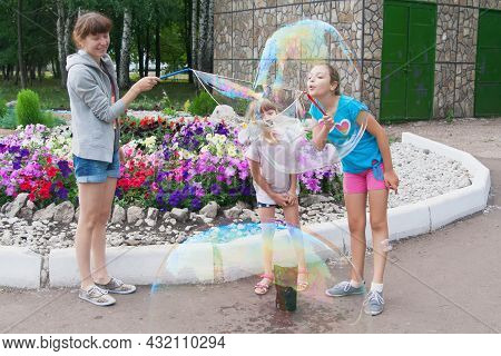 Two Sisters Blow Giant Bubbles With Mother Outdoor