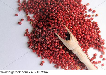 Pink Pepper On A White Background With A Wooden Spoon