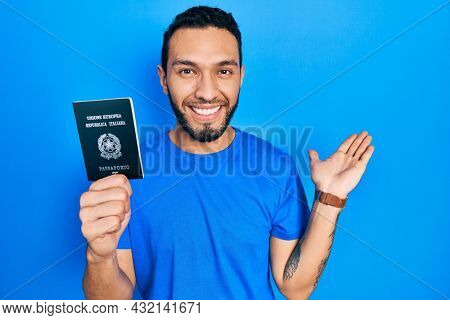 Hispanic man with beard holding italy passport smiling cheerful presenting and pointing with palm of hand looking at the camera. 