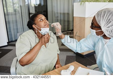 Black Young Woman Letting Doctor To Take Nasal Swab To Collect Sample To Covid-19 Test