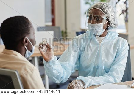 Medical Nurse In Protective Suit And Face Shield Telling Patient To Be Ready For Nasal Swab For Coro