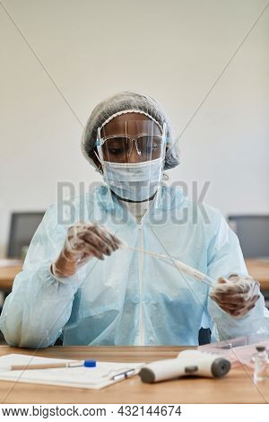 Serious Medical Nurse In Ppe Suit Putting Covid-19 Test Swab In Test Tube To Send To Laboratory