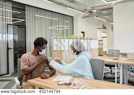 Medical Nurse In Safety Gloves And Protective Mask Giving Vaccine Injection Against Coronavirus To P