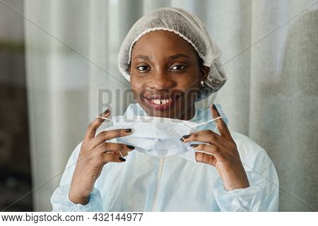 Face Of Pretty Smiling Young Black Nurse Taking Off Medical Mask From Sweaty Face
