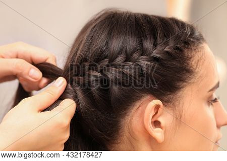 Professional Stylist Braiding Client's Hair On Blurred Background, Closeup