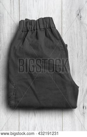 Folded Black Cargo Pants On White Wood Background