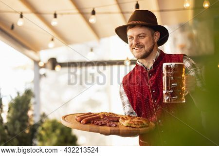 Happy Smiling Man, Waiter In Traditional Austrian Or Bavarian Costume Holding Mug, Glass Of Dark Bee