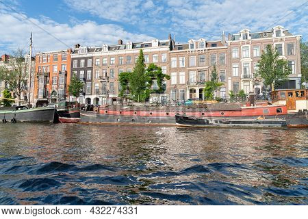 Amsterdam Netherlands - August 17 2017; Boats And Buildings Alongside Amstel River Including One Nam