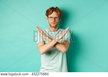 Serious And Confident Redhead Man In T-shirt And Glasses Saying No, Showing Cross Gesture To Stop Yo
