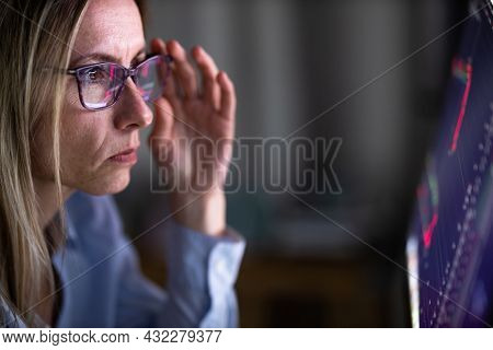Stylish mid-aged woman looking concerned while remote working from home, staring at the computer screeen for long hours, exhausting her eyes with blue light