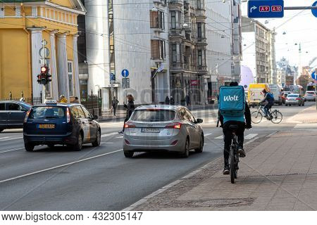 Riga, Latvia - 7 April, 2021: Wolt Food Bicycle Courier With A Bag Of Goods On The Street, Fast Deli