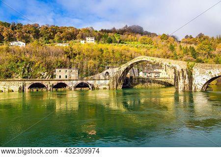 The bridge of Mary Magdalene is medieval structure that crosses the Serchio River. The green cold water of the river reflects the ancient asymmetrical arches. Italy, province of Tuscany