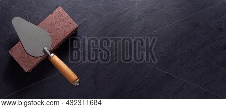 Construction trowel tool at brick on black background. Mason and bricks