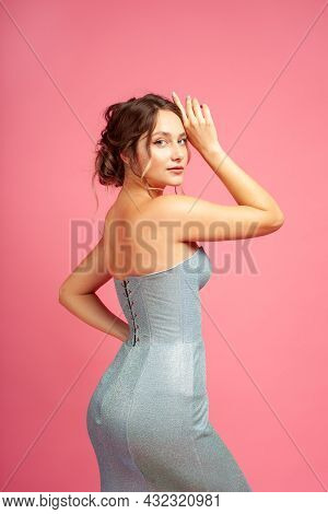Side View Of Attractive Causasian Woman In Blue Silver Tight Dress With Lacing On Pink Isolated Back