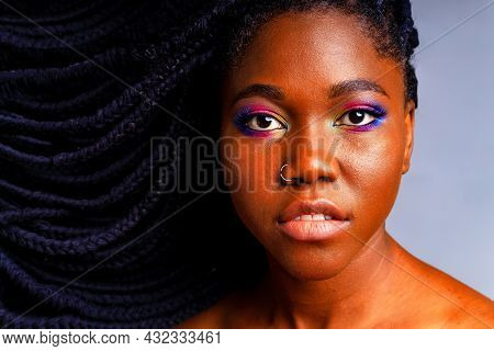 Hispanic Woman With Nose Piercing And Colorful Rainbow Make Up In Blue Studio Background