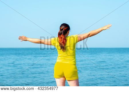 A Young Woman, Arms Outstretched, Is Enjoying A Summer Vacation By The Sea.