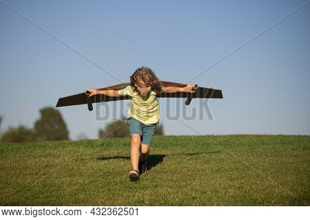 Child Boy Like A Pilot With Toy Wings Against Blue Sky. Kids Freedom Concept. Dreams Of Becoming A P