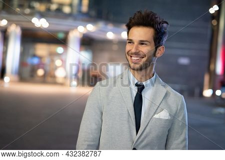 Portrait of a smiling businessman walking in a city at night