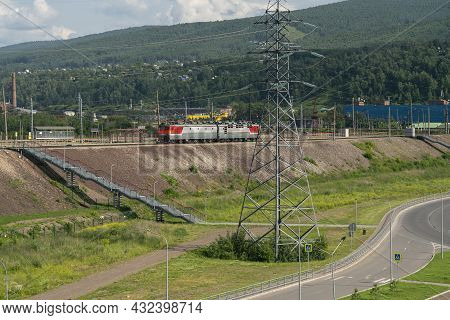 Electric Locomotive On Railway Tracks Against The Background Of Mountainous Terrain.