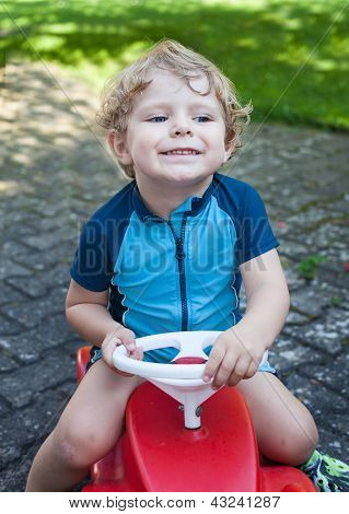 Todder menino brincando com carro de brinquedo grande