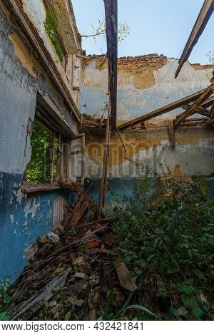 Broken Wooden Window And Room With Tall Grass, View Inside Of An Abandoned Half-destroyed Dormitory 