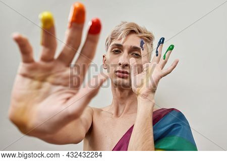 Young Transgender Looking At Camera And Posing With Fingers In Colorful Rainbow Lgbtqi Paint Isolate