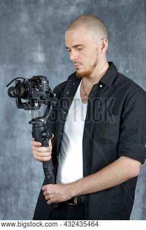 A Young Professional Videographer In A Black Shirt Holds A Professional Camera On A 3-axis Gimbal St