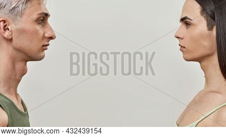 Side View Portrait Of Two Young Transgenders Looking At Each Other, Posing Isolated Over Light Backg