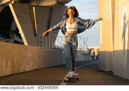 Young Carefree Woman Enjoy Riding Skateboard At Sunset. Happy Girl In Trendy Street Style Clothes, H