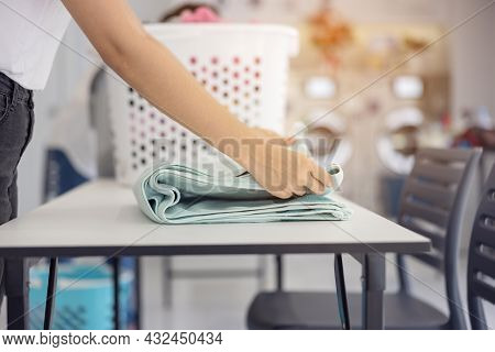 In The Self-service Laundry With Dryer Machines In The Backdrop, A Young Woman Enjoys Clean Ironed G
