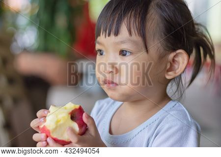Portrait​ Image​ Of​ 2-3 Yeas​ Old​ Of​ Baby.​ Happy​ Asian Child Girl Eating And Biting An Red Appl