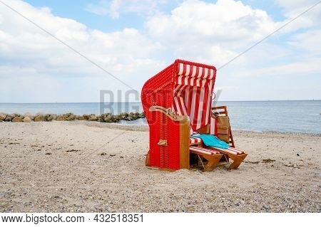 Traditional German Roofed Wicker Beach Chairs On The Beach Of Baltic Sea. Beach With Red Chairs On S