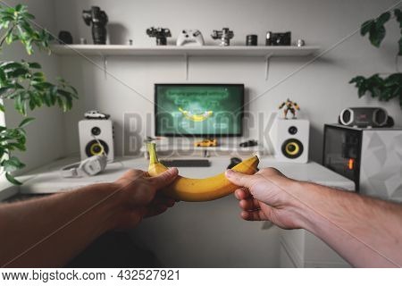Close-up Of Male Hands Holding White Wireless Banana-gamepad Against White Computer Dream Desk