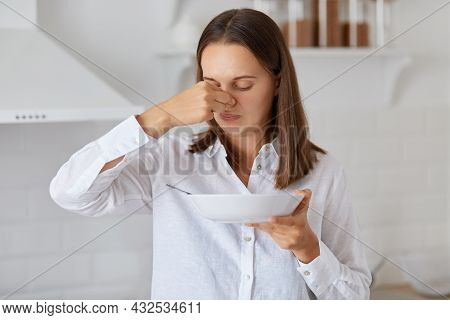 Indoor Shot Of Woman Standing With Plate In Hands, Does Not Want Eat Soup, Feeling Bad Smell, Pinchi